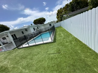 Full backyard artificial grass installation beside a swimming pool