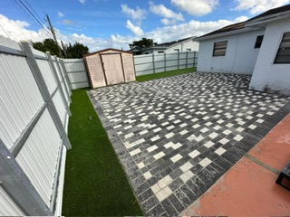 Black and white patterned paver patio with a turf border