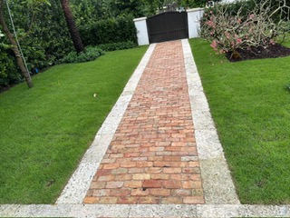 Chicago brick walkway with a keystone tile border through a green garden